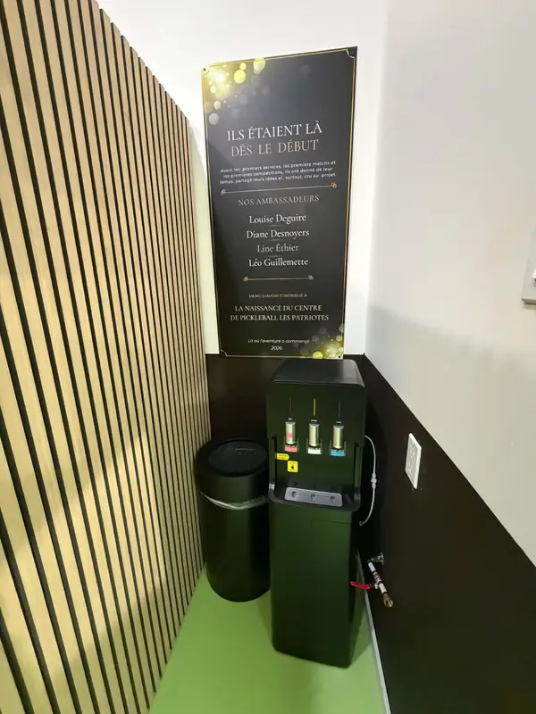 Distributeur d'eau chaude, tempérée et froide dans le vestiaire, sous la plaque des ambassadeurs du centre de pickleball
